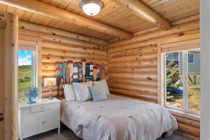 Cozy log cabin bedroom showcasing hand-crafted log walls with natural wood beams and ceiling details