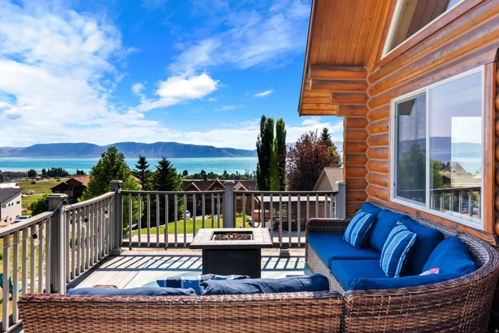 Waterfront deck with woven rattan seating, built-in cushioning, and panoramic lake and mountain vistas