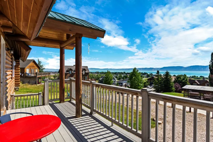 Elevated deck with composite railing and wood-finish flooring overlooking manicured lawn and mature landscaping