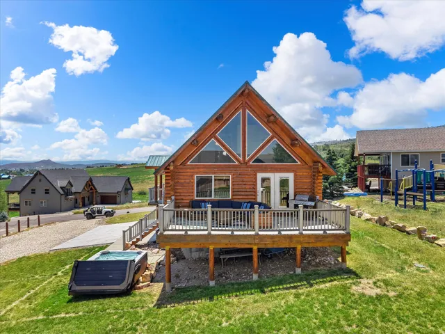 Modern A-frame residence featuring warm wood-finish siding, expansive front-facing gable with multi-pane glazing, and a wraparound deck with white balustrade railings