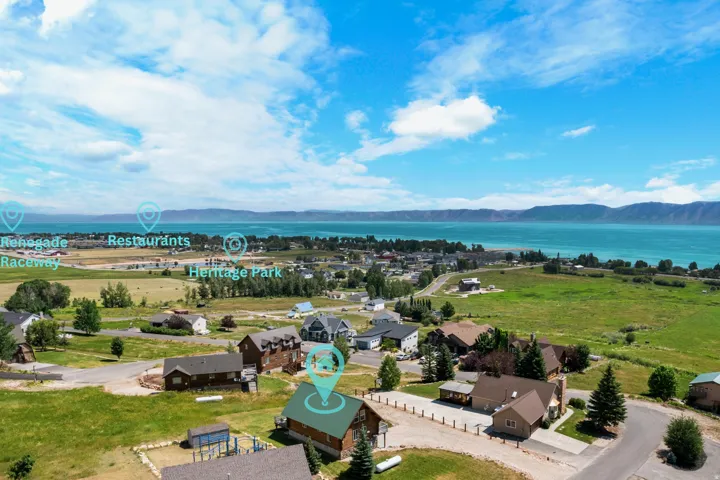 Sprawling rural estate featuring manicured grounds with mature landscaping, resort-style saltwater pool, multiple outbuildings and barns, expansive pastureland, and panoramic vistas of pristine lakefront and distant mountain ranges