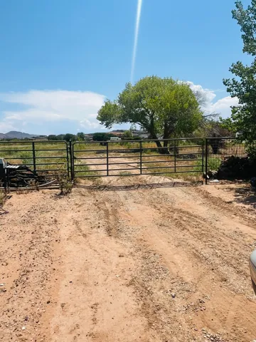 Gated entry leading to an expansive, undeveloped land area featuring mature trees and distant natural scenery