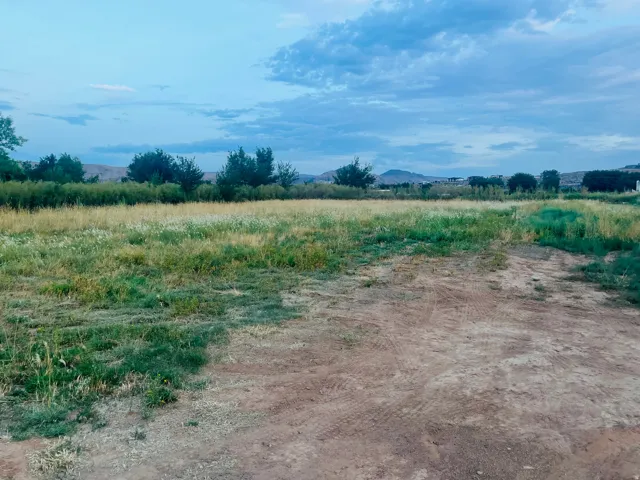 Expansive land parcel with varied natural ground cover and distant natural scenery
