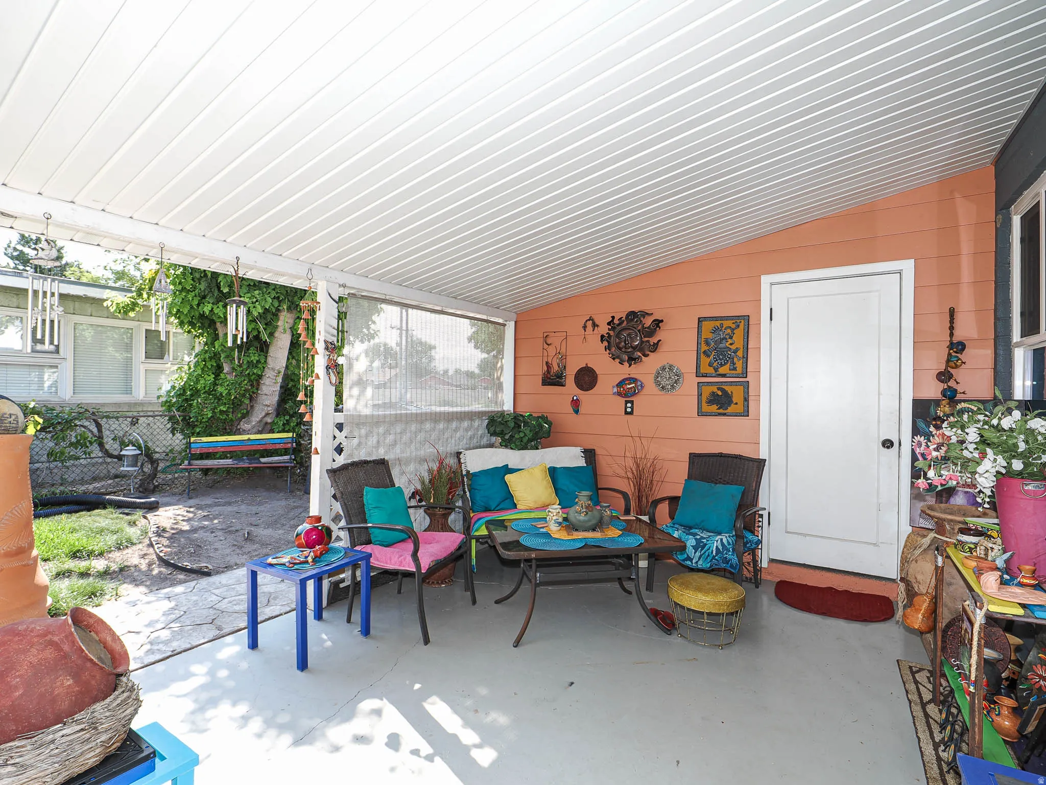 Covered patio with corrugated metal roof and screened enclosure, concrete flooring, and orange accent walls