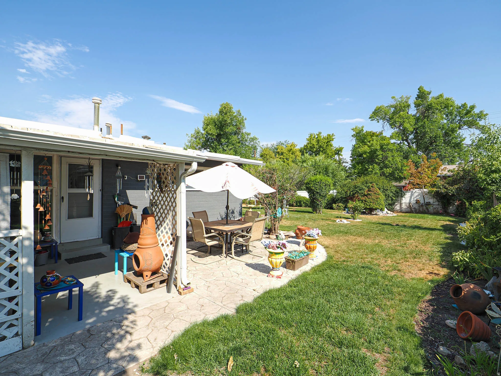 Expansive backyard featuring a concrete patio, mature trees, and a manicured lawn
