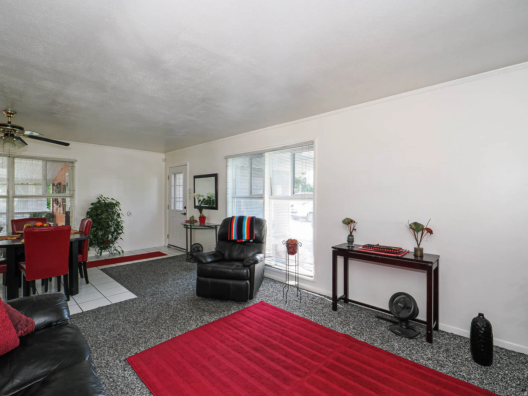 Spacious living area featuring polished aggregate flooring, expansive glass sliding doors with natural light, ceiling fan, and neutral wall finishes