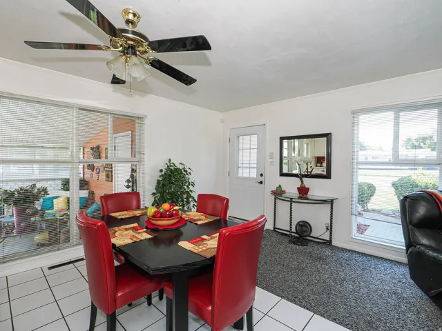 Bright dining area featuring a ceiling fan with integrated lighting, tile flooring, and large windows with natural light