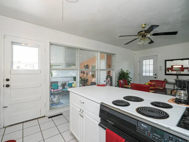 Bright kitchen featuring white cabinetry, tile flooring, and a coil-top electric range with four cooking surfaces