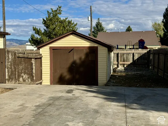 Detached single-car garage featuring light-colored horizontal siding, dual swinging doors, and a concrete driveway