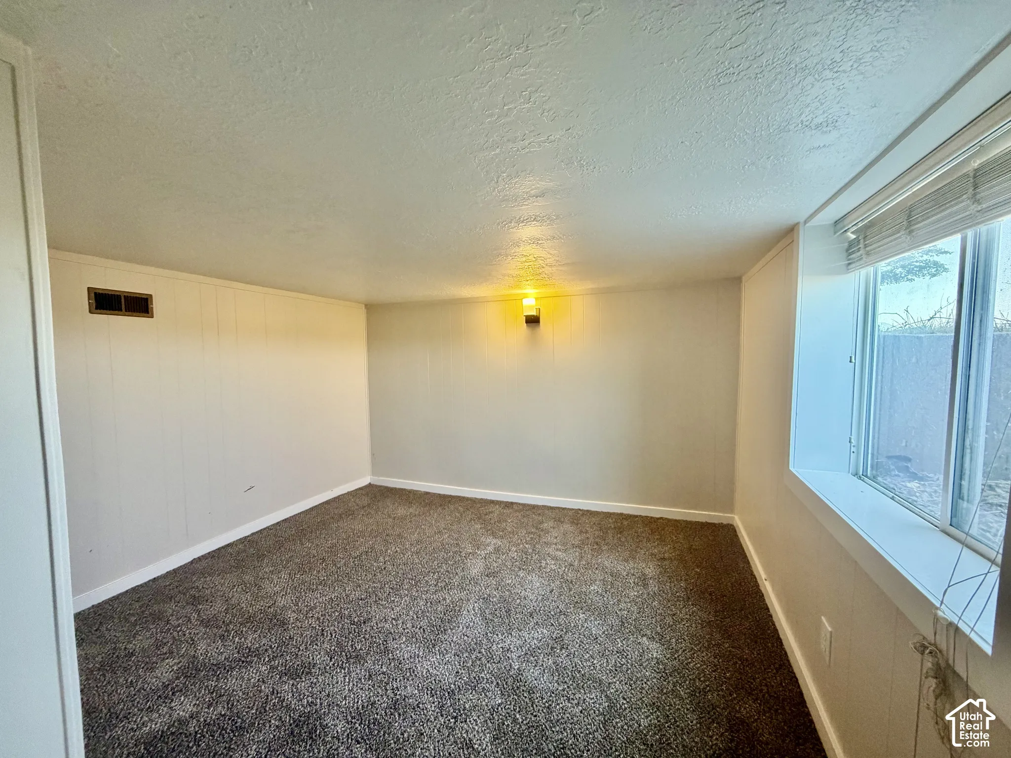 Spacious carpeted room with neutral wall finishes, recessed lighting, and large windows providing natural light