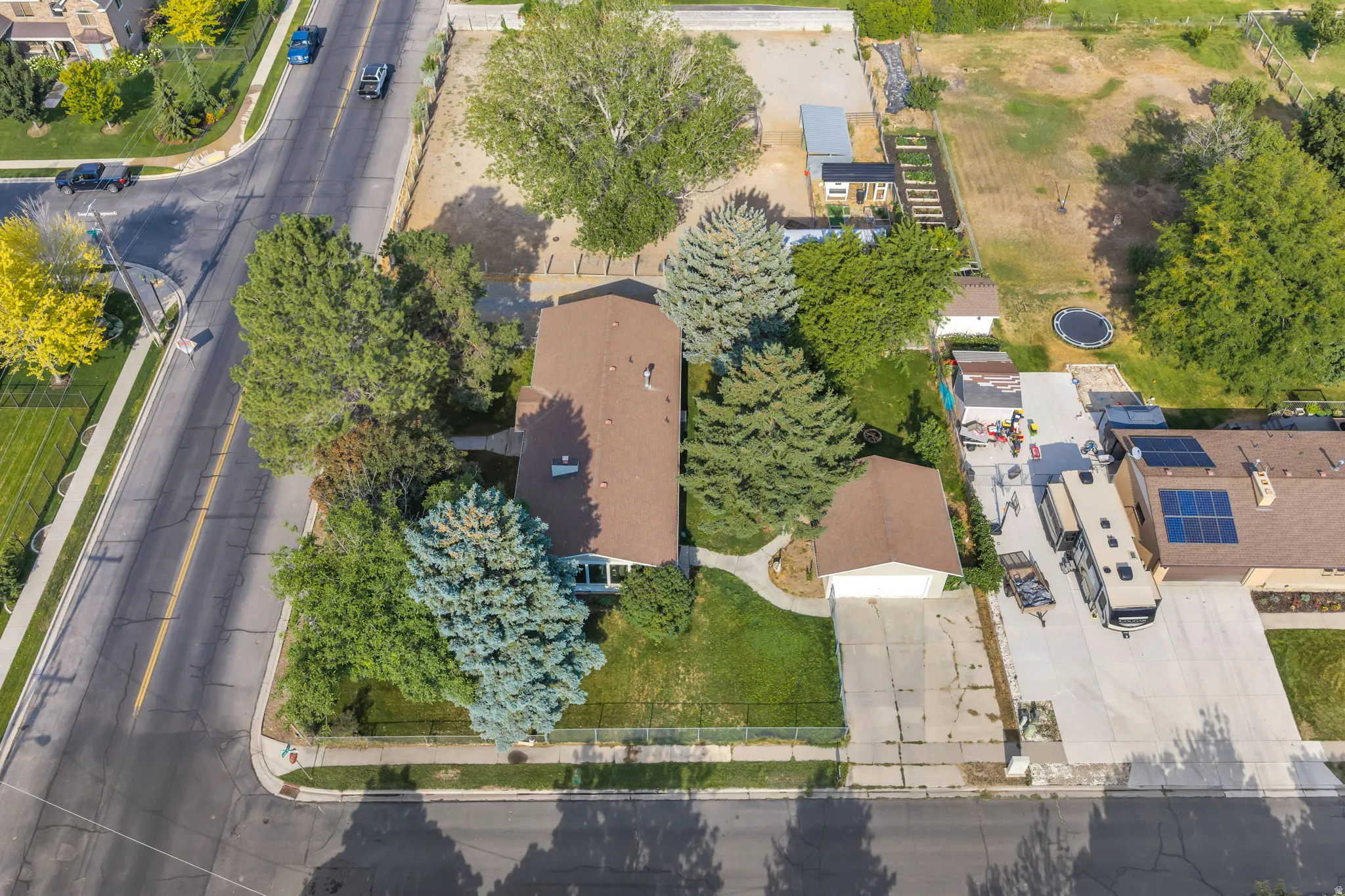 Aerial view of a residential property featuring a brick exterior home nestled among mature landscaping, including evergreen and deciduous trees