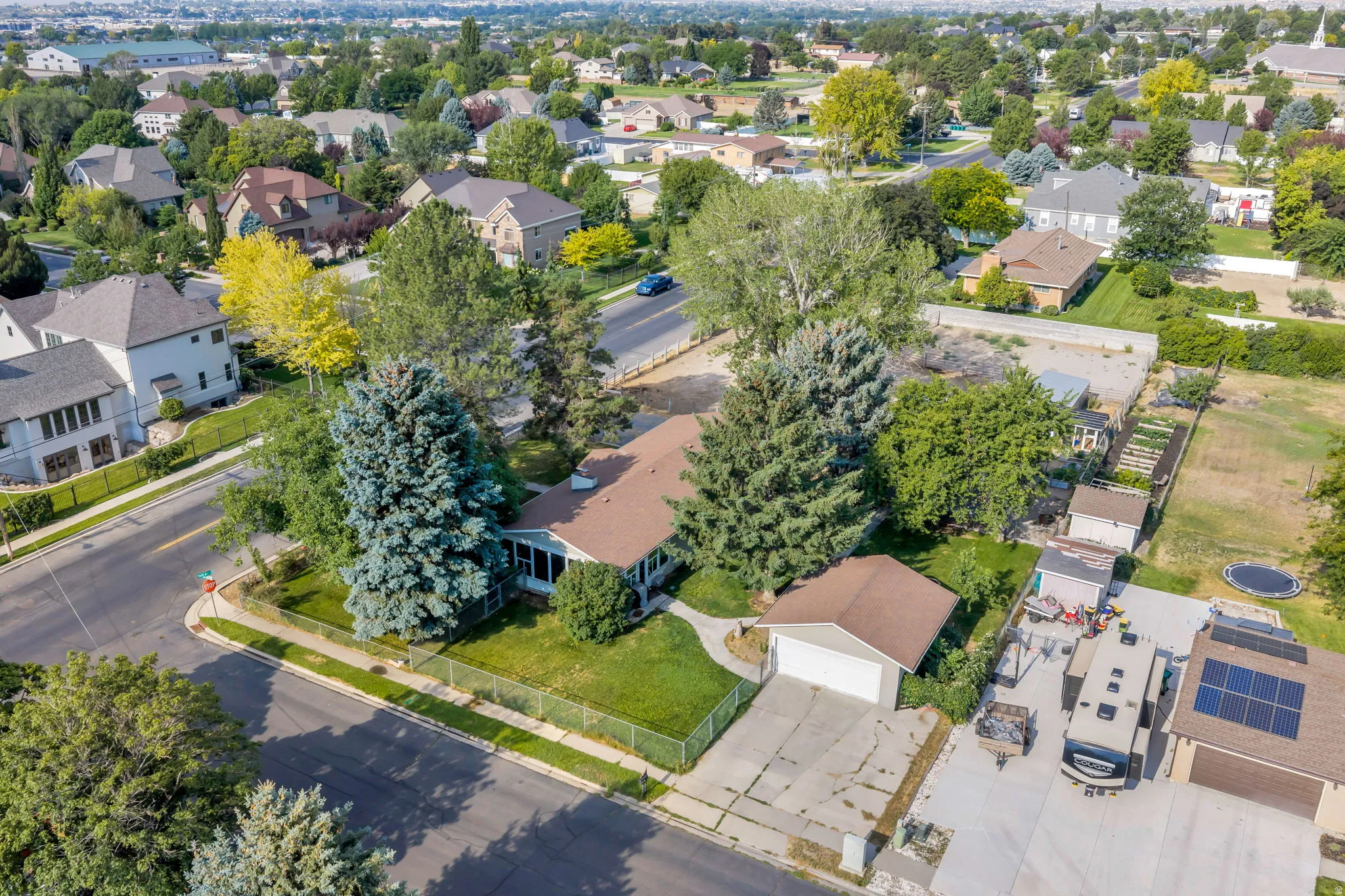 Ranch-style residence featuring a detached garage, established landscaping, and a fenced front yard