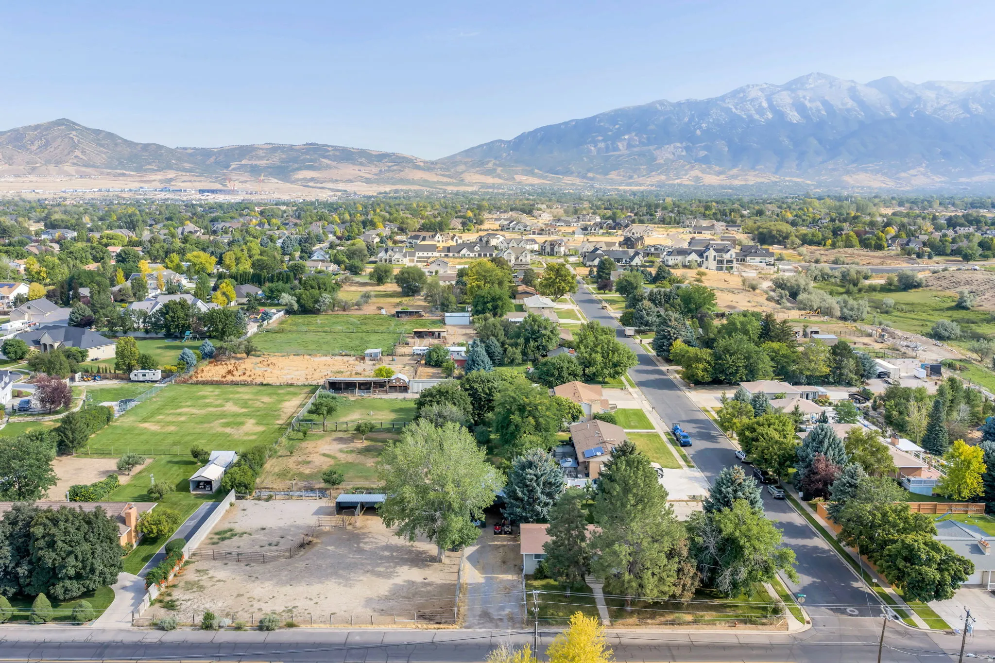 Aerial view showcasing expansive grounds with mature landscaping, multiple residential structures, manicured lawn areas, and mountain backdrop