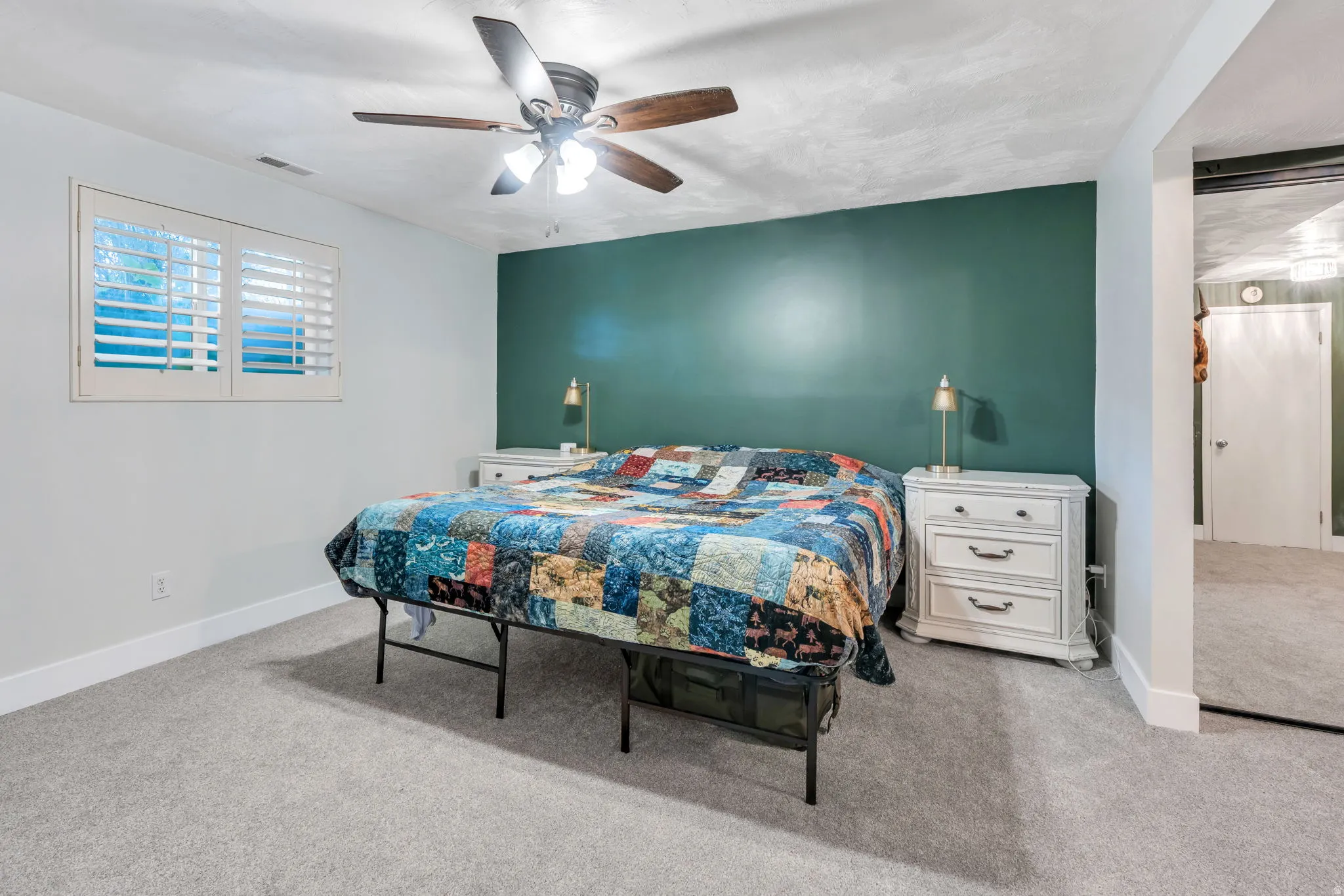 Spacious bedroom with a dramatic teal accent wall, recessed lighting, and brushed nickel ceiling fan