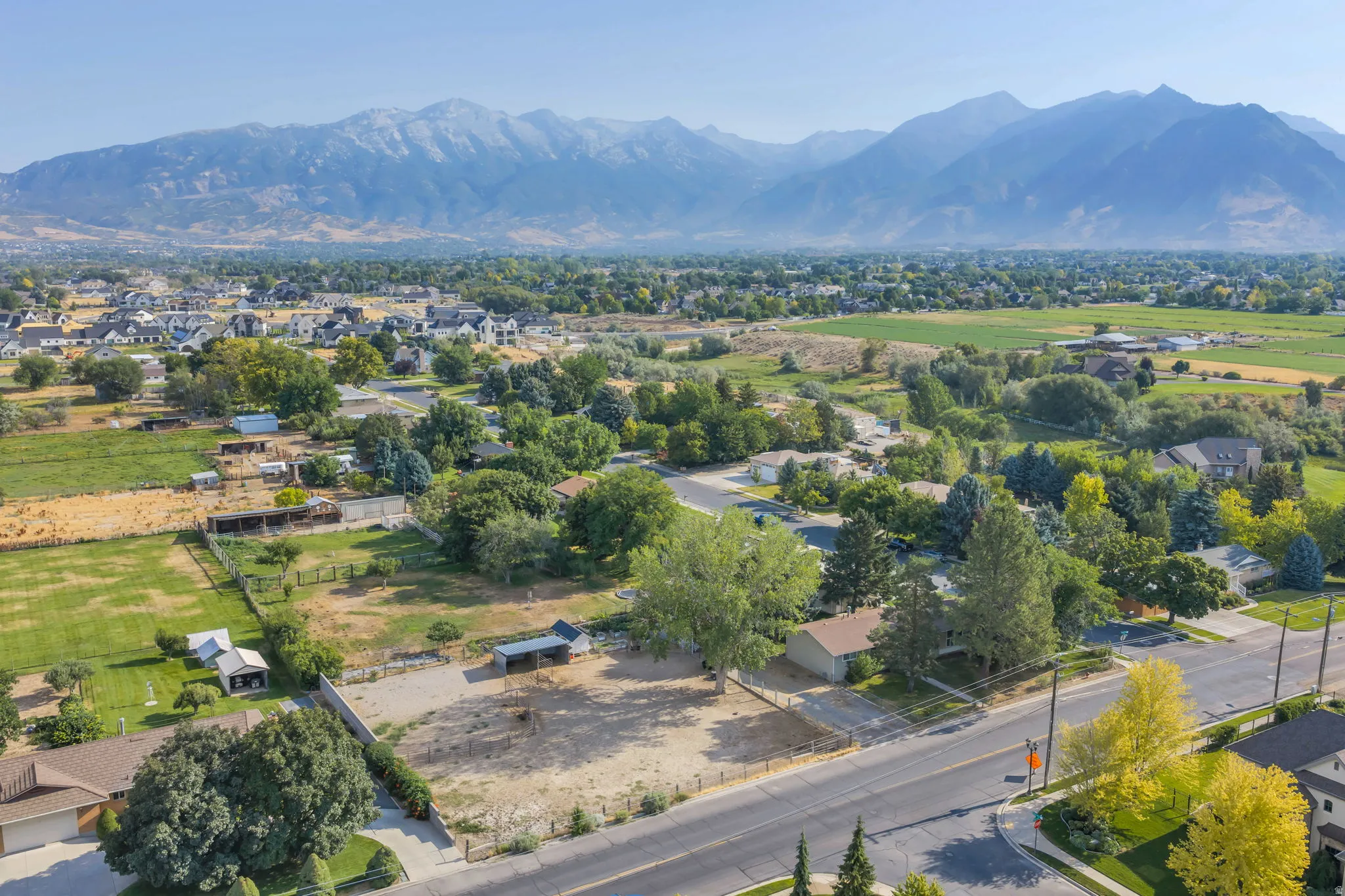 Expansive mountain range backdrop, mature tree coverage, paved roadways, and residential development