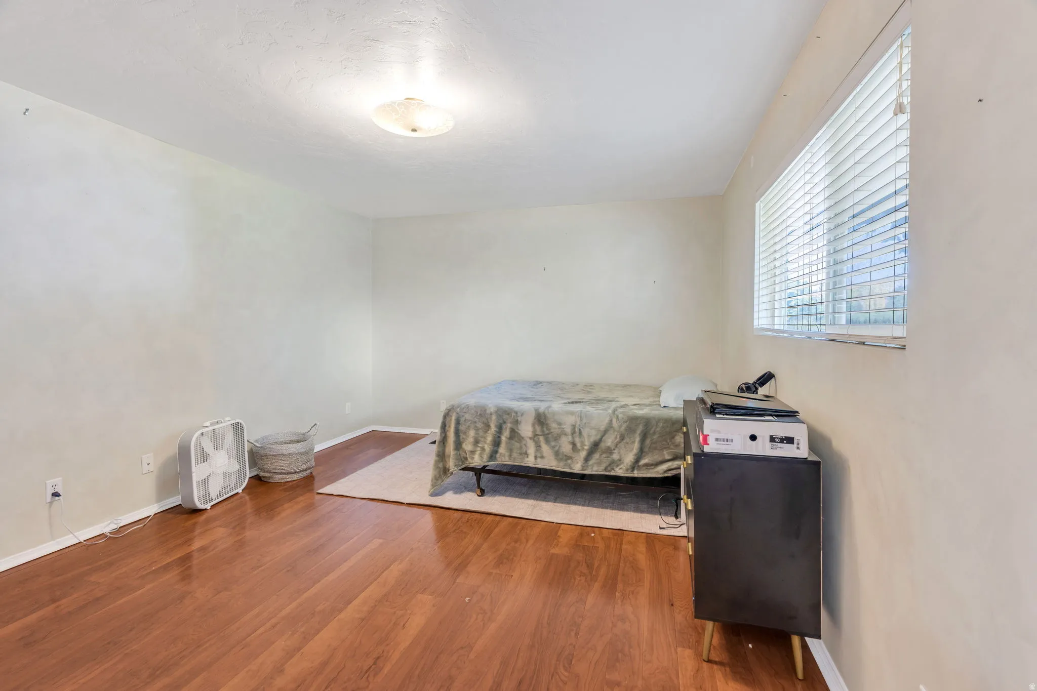 Wood-finish flooring, white walls, and a window with horizontal blinds