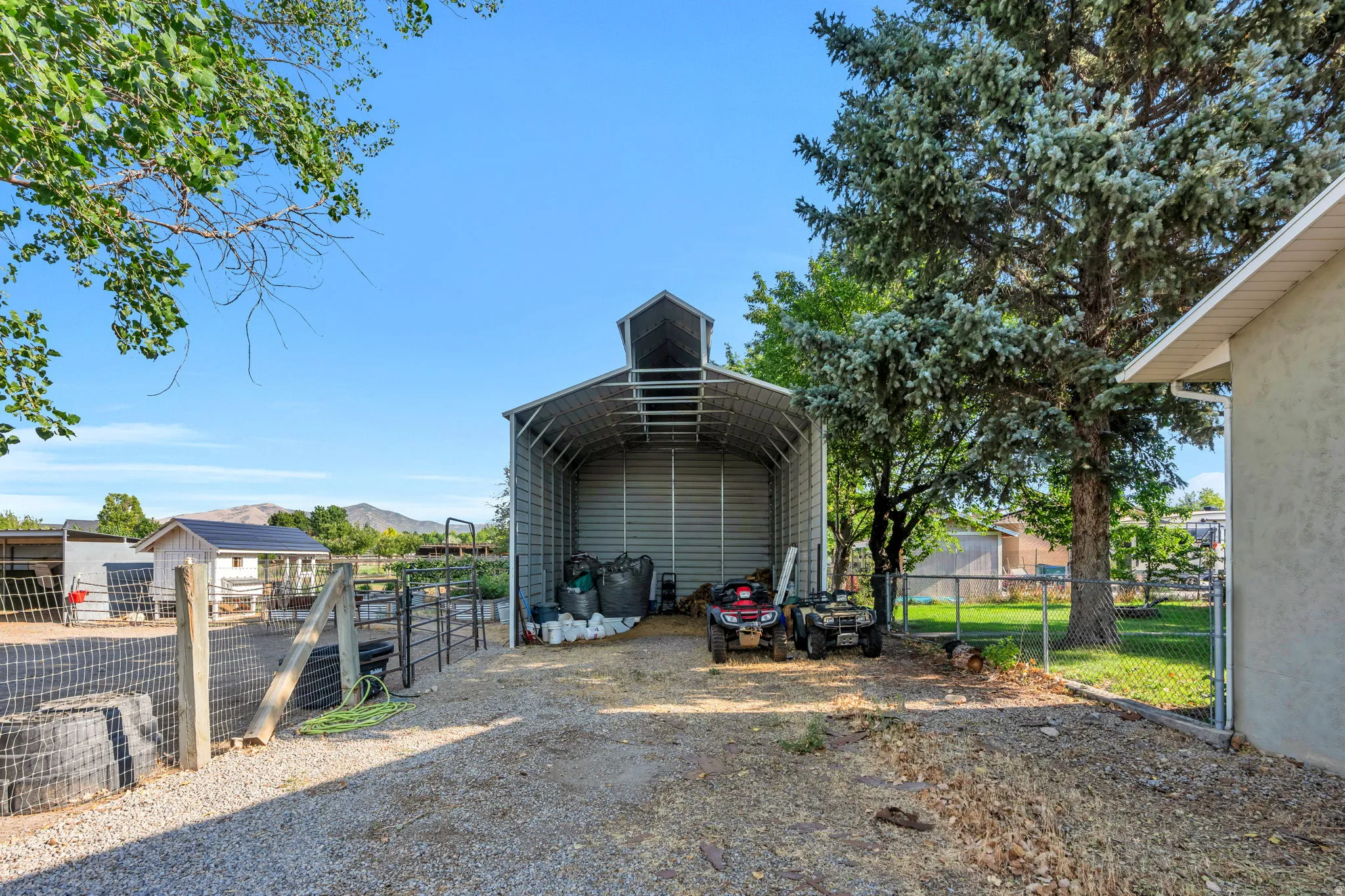 Gravel driveway leading to a metal-frame open-sided structure with a gabled roof