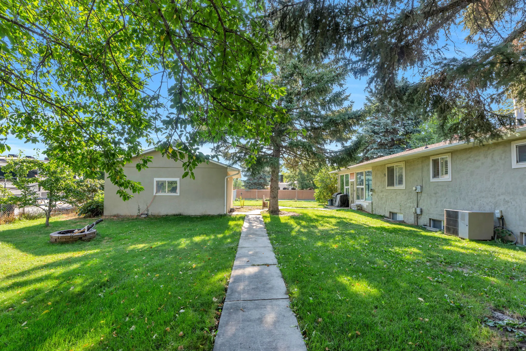 Mature landscaping and lush lawn create an inviting outdoor setting, anchored by a concrete walkway leading through the center of the property