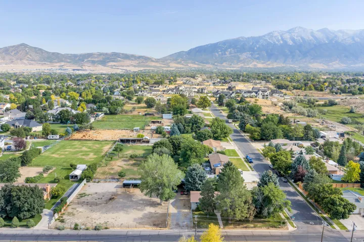Aerial view showcasing expansive grounds with mature landscaping, multiple residential structures, manicured lawn areas, and mountain backdrop