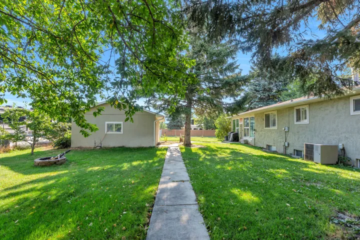 Mature landscaping and lush lawn create an inviting outdoor setting, anchored by a concrete walkway leading through the center of the property