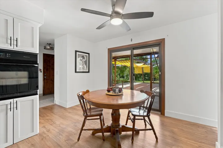 Bright dining area with wood-finish flooring, a round pedestal dining table, and French doors opening to the outdoor patio