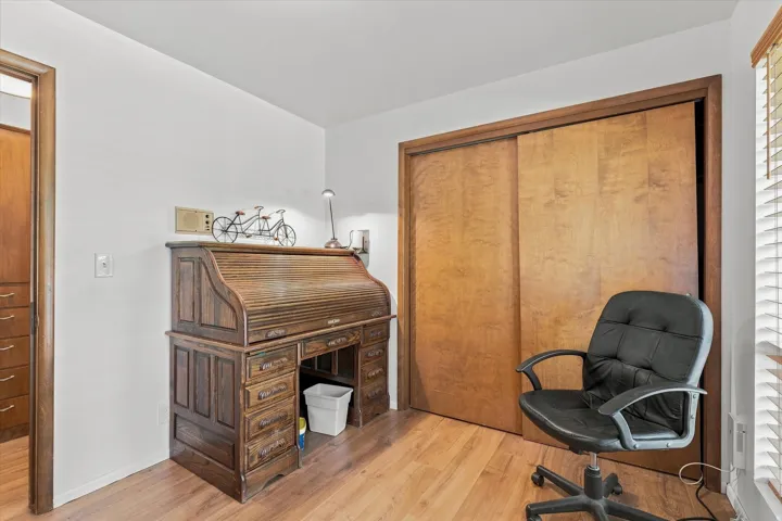 Wood-finish flooring with a closet featuring wood sliding doors and trim