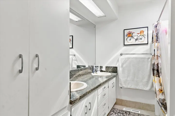 Dual vanity with integrated sinks, dark stone-finish countertop, and under-counter storage