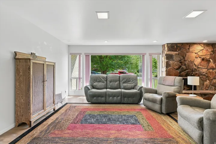 Spacious living area featuring a stone fireplace, large windows, and recessed lighting