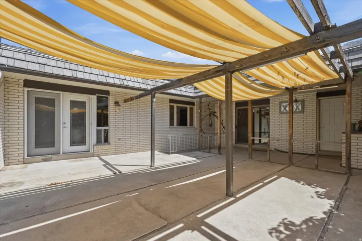 Expansive covered patio with retractable yellow shade system and sturdy metal pergola framework, offering flexible sun protection over composite decking