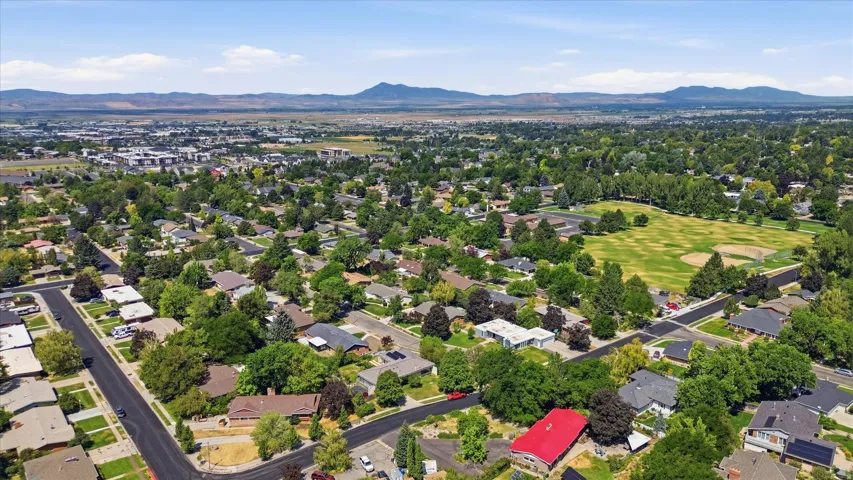 Aerial view showcasing this residential property nestled within an established neighborhood featuring mature trees, manicured landscaping, and surrounding single-family homes