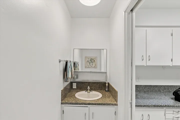 Elegant bathroom vanity featuring a round ceramic sink, granite-style countertop, and white cabinetry with polished hardware