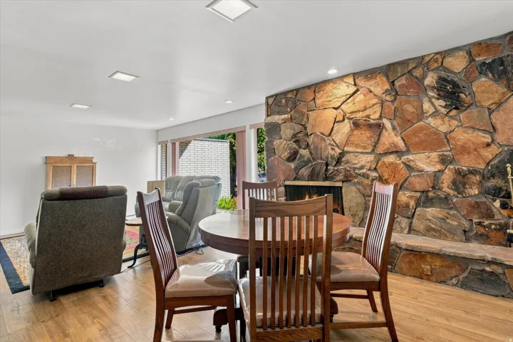 Wood-finish flooring throughout, featuring a stone accent wall with an integrated fireplace and hearth