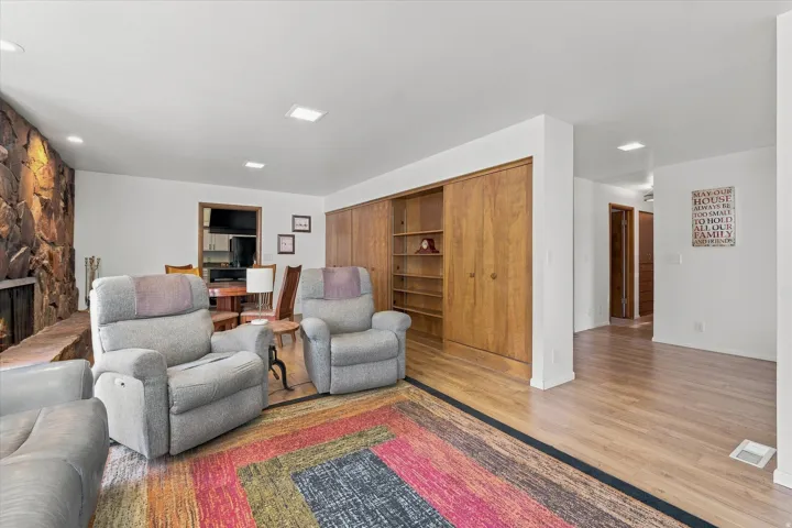 Accent stone fireplace with hearth, recessed lighting, built-in shelving, wood-finish flooring, and wood-finish closet doors