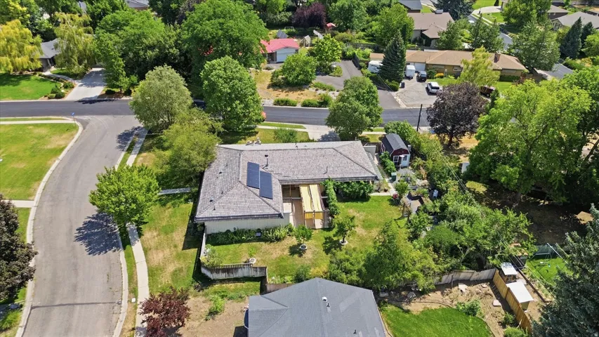 Residential property featuring a shingled roof, solar panels, and mature landscaping