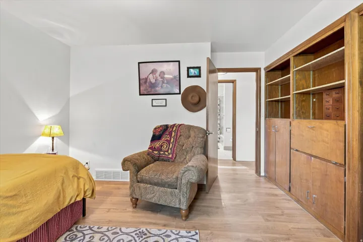 Wood-finish flooring throughout, bright white walls, and built-in wood cabinetry with shelving