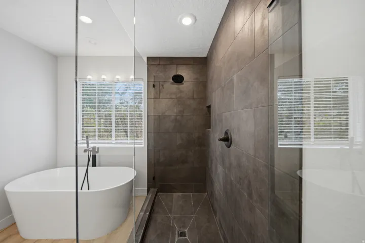 Walk-in shower with large format tile, recessed niche, and dark bronze fixtures