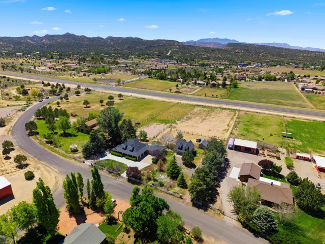Scenic rural property featuring a contemporary residence with dark metal roofing, surrounded by mature landscaping and established trees