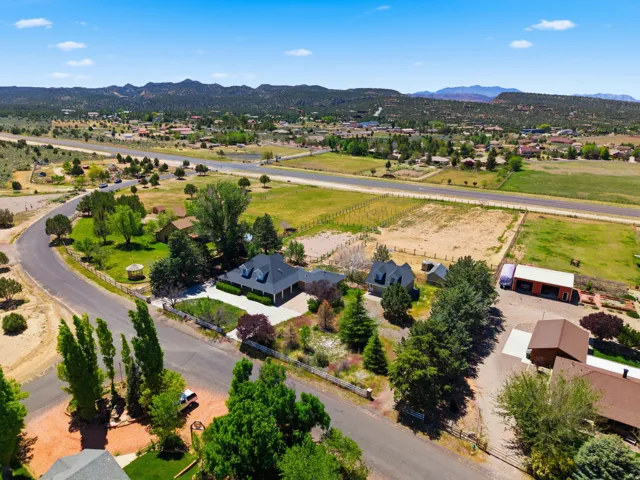 Aerial view showcasing a residence set on expansive grounds with mature landscaping, including Italian cypress trees and established plantings