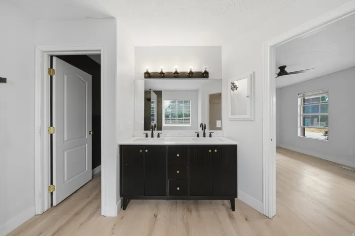 Double vanity with white countertop, black cabinetry, and brass hardware