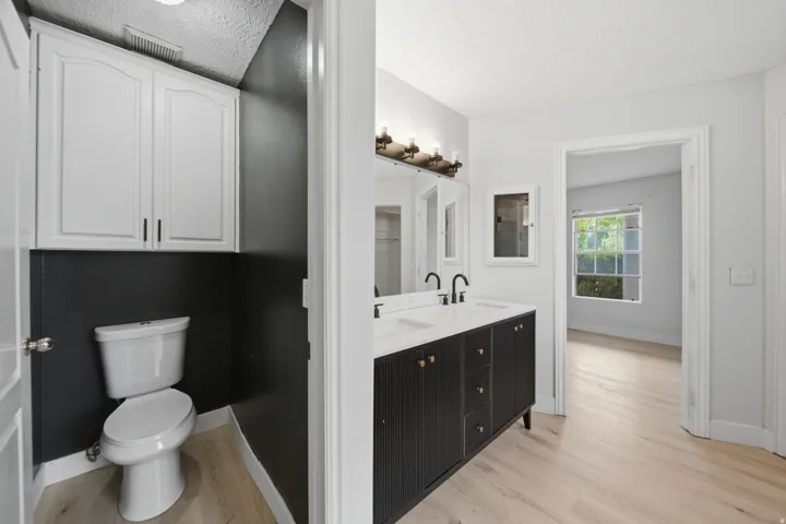 Primary bathroom featuring a dual-sink vanity with black cabinetry, white countertop, and matte black faucetry