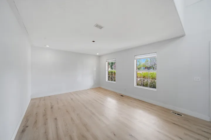 Wood-finish flooring with white walls, recessed lighting, and dual windows