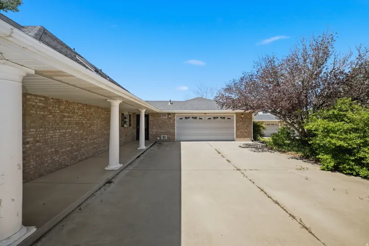 Expansive driveway with concrete surface leading to a two-car garage featuring a paneled garage door