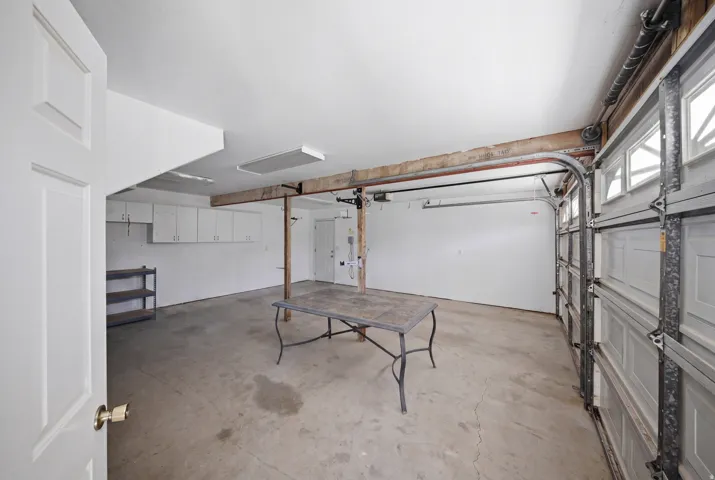 Garage with concrete flooring, overhead fluorescent lighting, and built-in white cabinetry
