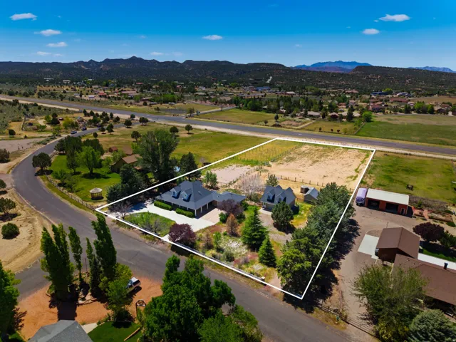 Expansive property with a primary residence, a detached secondary structure, and a large undeveloped parcel