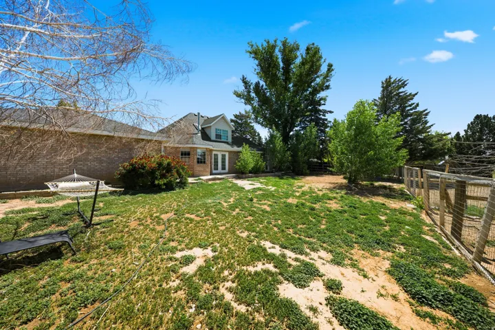 Expansive backyard featuring mature trees, open lawn space, and wooden perimeter fencing