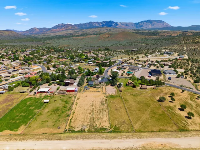 Expansive rural landscape featuring a mountainous backdrop, scattered residential structures, and undeveloped land