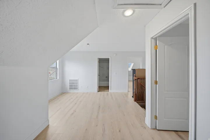 Attic space with light wood-finish flooring, recessed lighting, and a white paneled door