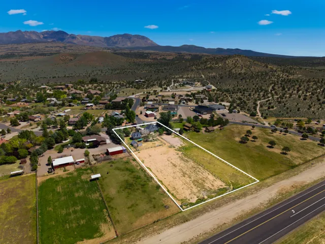 Vacant land parcel with approximately 5+ acres, bordered by paved road frontage and situated within an established residential community