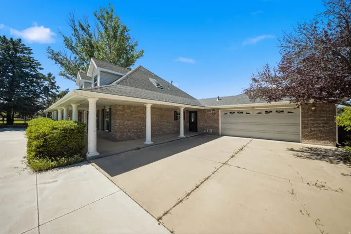 Brick exterior with a covered entryway, multiple columns, attached garage, and dormer windows