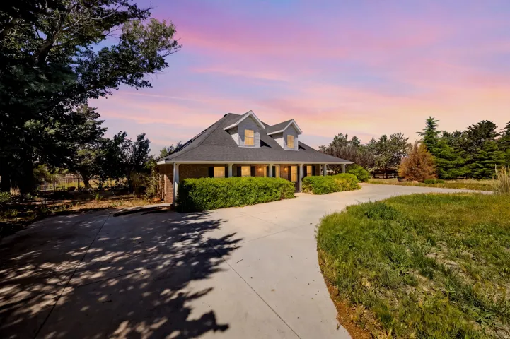 Charming residence featuring a gabled roofline with dormer windows, welcoming front entrance, and curved driveway approach